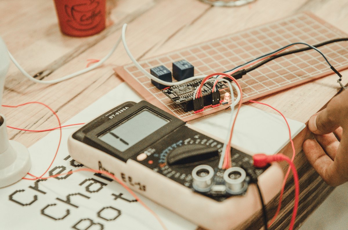 Hand holding a multimeter while testing an electrical circuit